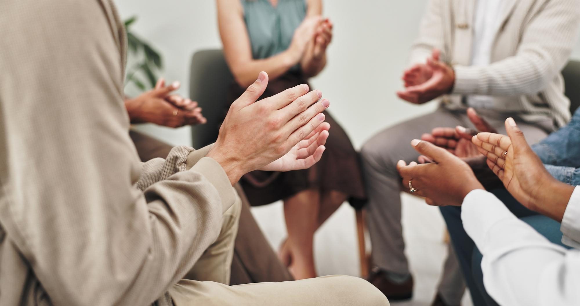 Close-up of individuals clapping and engaging during a supportive group therapy discussion focused on emotional wellness and recovery in Columbus.