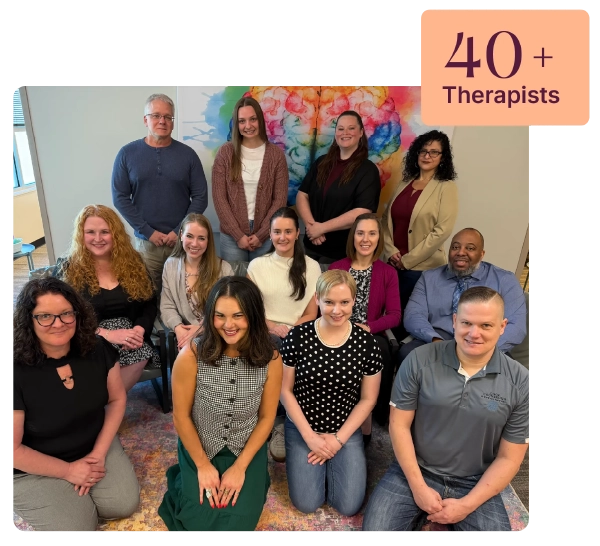 Group of therapists posing in front of colorful brain artwork